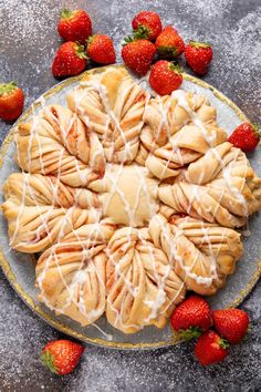 a plate topped with pastry covered in icing next to strawberries