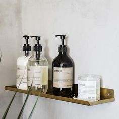 three bottles of soap and lotion sitting on a shelf