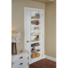 a white door is open to reveal a pantry with many items on the shelves and drawers