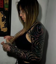 a woman with tattoos on her arms and arm is holding something in her right hand