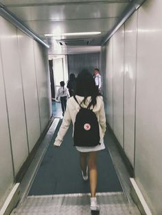 a woman with a backpack walking down a hallway