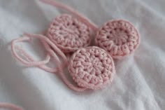 three pink crocheted buttons sitting on top of a white sheet with the words come fare botonii