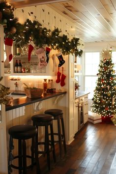 a kitchen decorated for christmas with stockings hanging from the ceiling