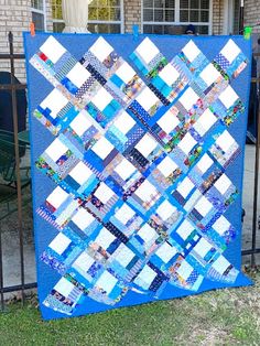 a blue and white quilt is hanging on a metal fence in front of a house