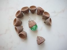 some cones and green glass beads are arranged in a circle on a white table top