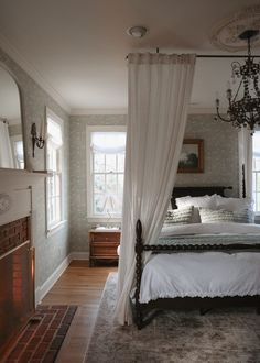 a bedroom with a bed, fireplace and chandelier hanging from it's ceiling