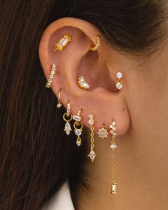 a close up of a person wearing gold ear piercings with diamond drops and chains