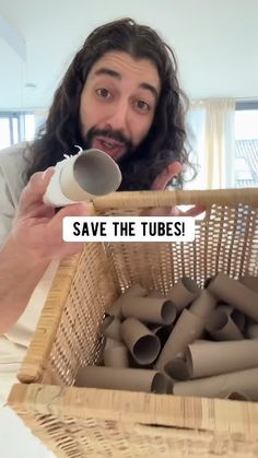 a man with long hair holding a cup in front of a basket filled with tubes