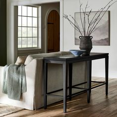 a living room filled with furniture and a vase on top of a table in front of a doorway