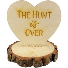 a wooden heart with the words the hunt is over on it sitting on top of a tree stump