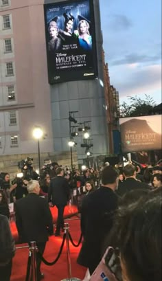 a crowd of people standing on top of a red carpet next to a tall building