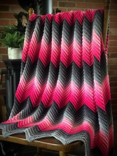 a pink and gray blanket sitting on top of a wooden chair