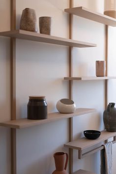 some shelves with vases and other items on them in a room that has white walls