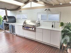 an outdoor kitchen with white cabinets and stainless steel appliances