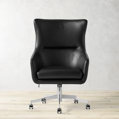 a black office chair sitting on top of a hard wood floor next to a white wall