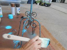 a person is using a paintbrush to paint a wrought iron stand