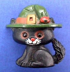 a black cat figurine wearing a green fireman's hat