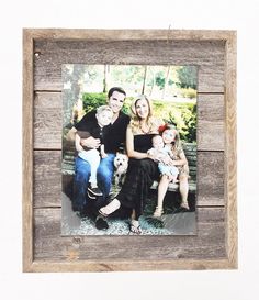 a family sitting on a bench with their dog in front of them and holding the baby