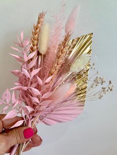 a person is holding some pink flowers in their hand and gold foil on the wall behind them