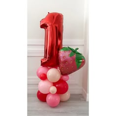 a number one balloon and some balloons in the shape of strawberrys on top of each other