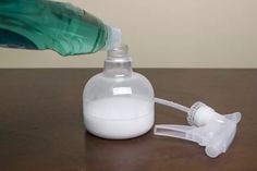 a bottle filled with white liquid sitting on top of a table next to a pump