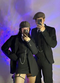 two people taking pictures with their cell phones in front of a purple background and blue lights