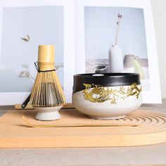 a white vase sitting on top of a wooden table next to a golden dragon decoration