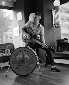 a man sitting on top of a chair next to a guitar