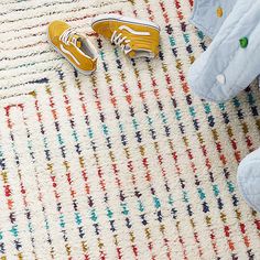 a pair of yellow shoes sitting on top of a rug next to a stuffed animal