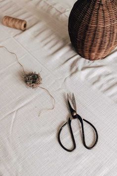 a pair of scissors sitting on top of a bed next to a ball of thread