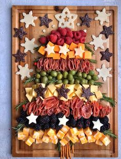 a christmas tree made out of fruits and cheeses on a cutting board with stars