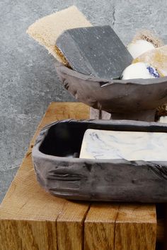 an old wooden box with soap and sponges in it sitting on a block of wood