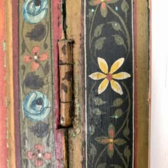 an old wooden door with floral designs painted on the front and side panels, has a metal latch