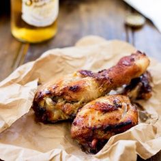 two pieces of chicken sitting on top of a piece of wax paper next to a bottle of beer