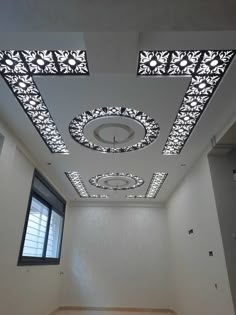 an empty room with white walls and decorative ceiling tiles on the ceiling is lit by recessed lights