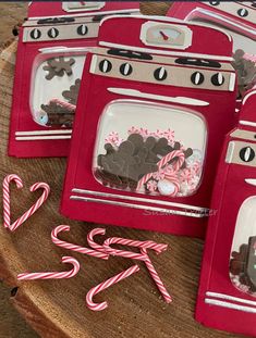 several red boxes with candy canes and candies in them sitting on a wooden table