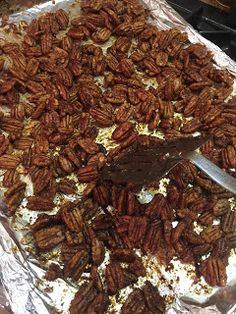 pecans are on top of tin foil with a spatula