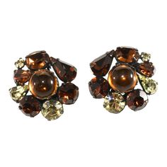 This is part of Chairish’s Costume Jewelry assortment.  Vintage clip earrings embellished with central amber-colored cabochon stones surrounded by brown and yellow faceted rhinestones in varying shapes and sizes. Settings are gun metal plated. These are unmarked - have a look similar to Regency jewelry. We believe they date to the late '50s or early 1960s. Measure 1" long and a little over 1" wide. Condition is excellent. Regency Jewelry, 50s Jewelry, Antique Costume Jewelry, Vintage Clip Earrings, Elvis Presley Photos, Vintage Collage, Christmas Pins, Vintage Clip, Amber Color