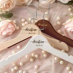 two wooden wedding hangers with personalized names on them and flowers in the background