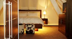 a bed with two cow hide ottomans on the floor in a room that looks like an attic