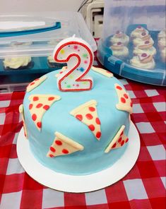 a birthday cake with the number two on it and some cupcakes in the background