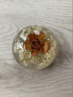 a flower in a glass vase on a wooden table with wood grains and other things