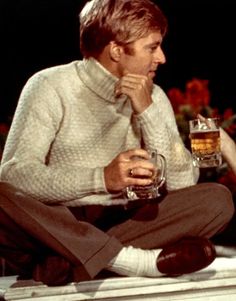 a man sitting on the ground holding a glass of beer