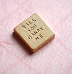 a small wooden magnet with the words will you marry me written on it's side