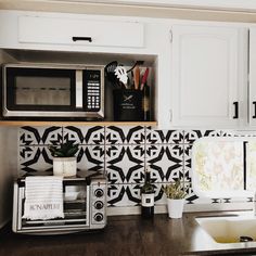 a kitchen with white cabinets and black and white tile on the backsplash is shown