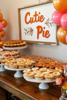 several pies and other desserts on a table with balloons in the back ground