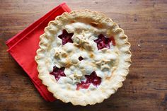 a pie sitting on top of a wooden table next to a red napkin and fork