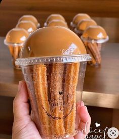 a person holding up a plastic cup filled with churros