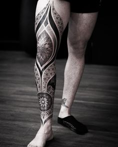 a man's leg with tattoos on it and his foot in black and white