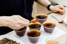 a person sitting at a table with cups of coffee and spoons in front of them